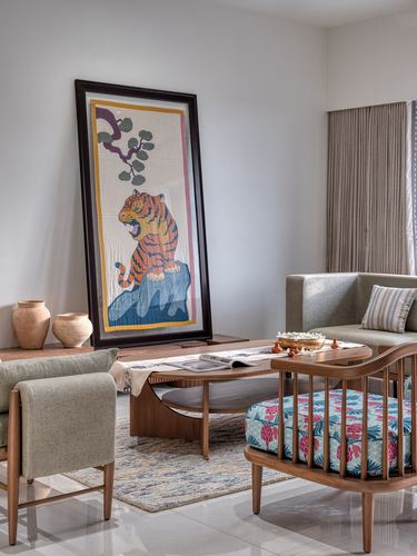 Living room with tiger tapestry art, wood coffee table, sage sofa, and floral cushioned bench