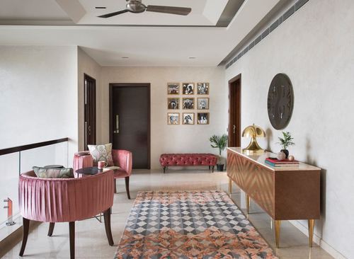 Jaipur home foyer with pink velvet chairs, patterned rug, console table and gallery wall