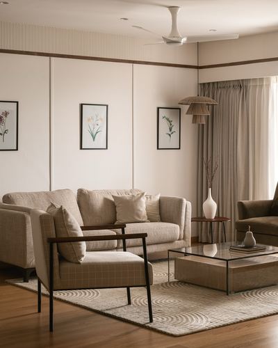 Beige living room with paneled walls, cane pendant light, glass coffee table, and patterned rug