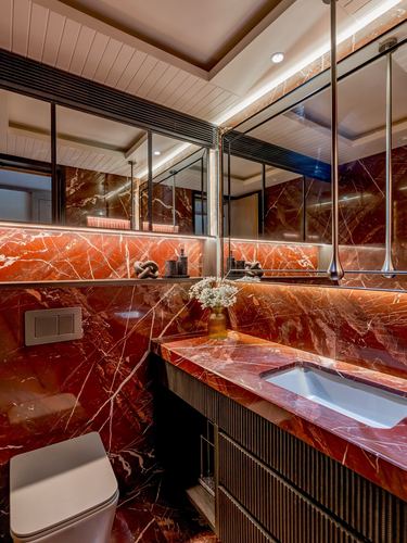 Bathroom vanity in deep red veined marble with backlit mirror and brass fittings