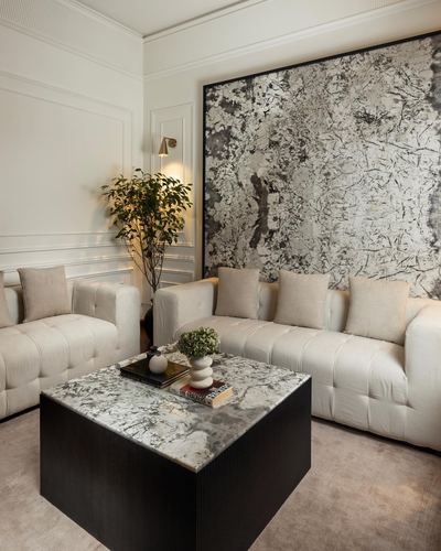Neutral living room with tufted sofas, dark marble coffee table, and large abstract wall art