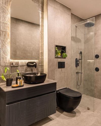 Bathroom with black vessel sink, arched backlit mirror, and glass-enclosed shower with black fixtures