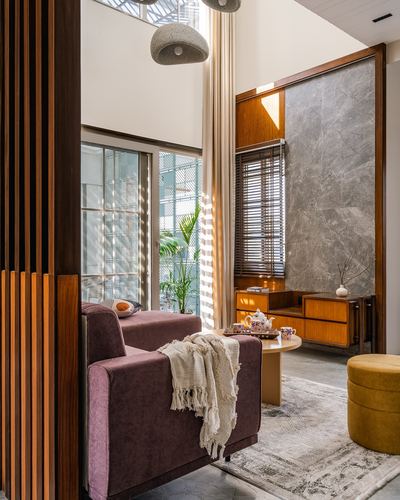 Living room nook with mauve armchair, wood slat screen, and marble-look feature wall in daylight