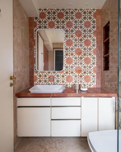 Bathroom vanity with floral tile backsplash, stone countertop, white cabinetry and rectangular mirror