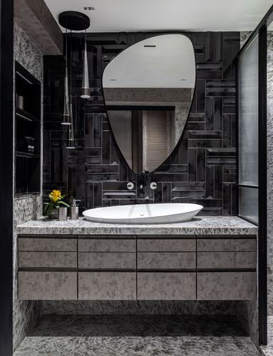 Dark stone bathroom vanity with freeform white sink and irregular asymmetric mirror