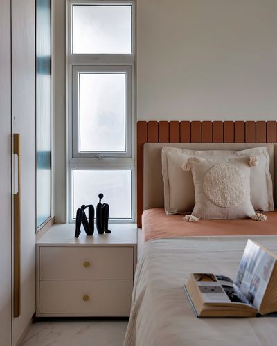 Bedroom corner with fluted terracotta headboard, cream bedding, nightstand and tall window