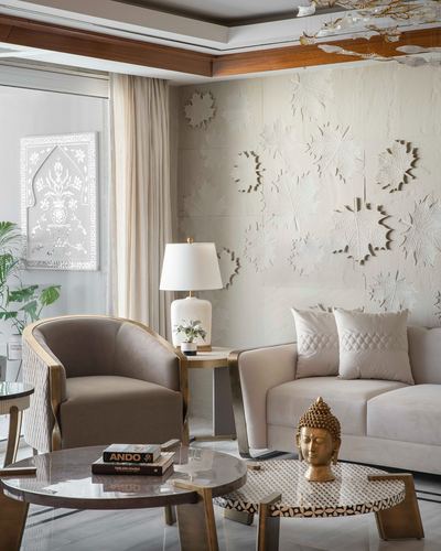 Living room with cane armchair, beige sofa, brass buddha head, and sculpted leaf wall panel