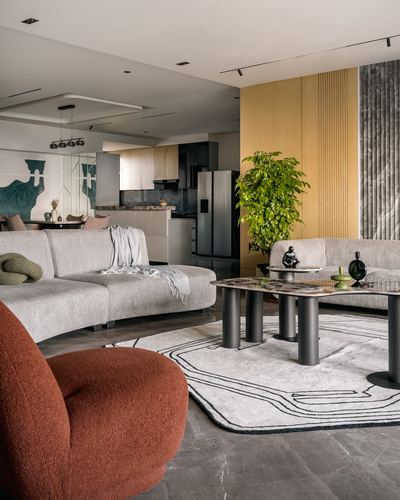 Curved beige sofas and terracotta armchair around sculptural coffee tables in modern living room