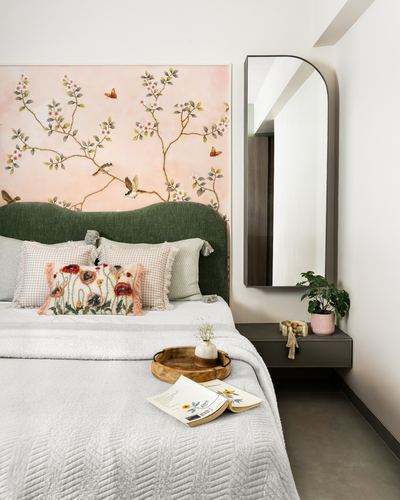 Bedroom with green upholstered headboard, floral mural, arched mirror and floating nightstand