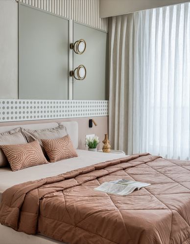 Japandi-style bedroom with sage headboard panel, brass sconces, and rose-toned quilted bedding