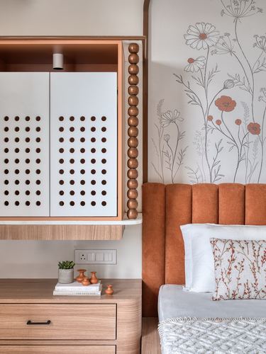 Bedroom corner with perforated cabinet, wooden bead trim, floral mural wall, and terracotta channel-tufted headboard
