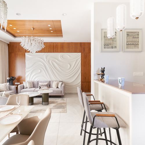 Open-plan living, dining and bar area with carved white wall panel and grey sofas