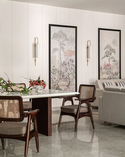 Dining area with cane-back wooden chairs, marble-top table, and framed botanical art on paneled wall