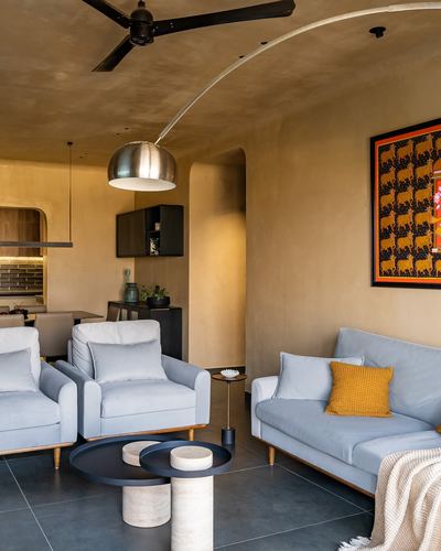 Living room with blue sofas, mustard cushion, arched wall niche and framed textile art