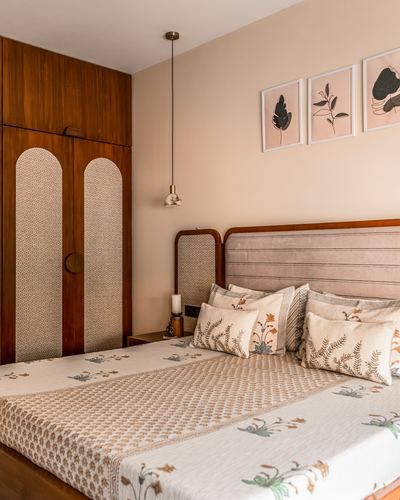 Bedroom with cane-paneled wooden wardrobe, pink channel-tufted headboard, and floral block-print bedding