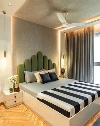 Bedroom with green scalloped velvet headboard, striped bedspread, and backlit textured wall