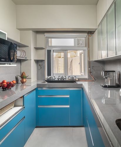 U-shaped kitchen with teal cabinets, grey stone counters, and a window above the gas hob