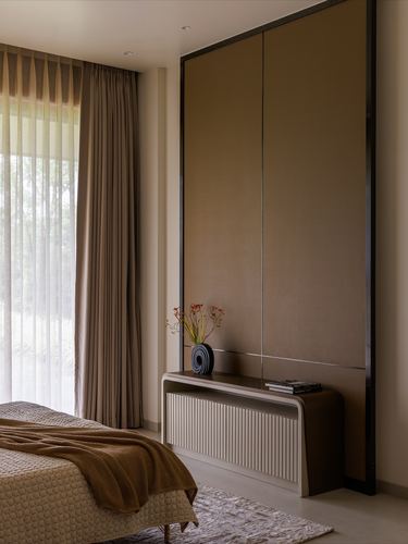 Bedroom corner with fluted console below a large dark bronze framed wall panel and layered curtains