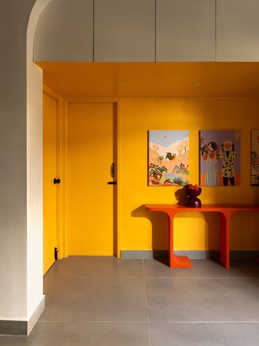 Mustard yellow entryway with red console table and colorful artwork under an arched ceiling