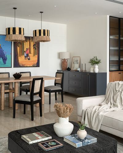 Open living-dining space with cane chairs, fringed pendant lights, dark sideboard and beige sofa