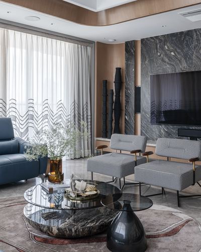 Living room with marble tv wall, houndstooth chairs, navy sofa, and round marble coffee tables