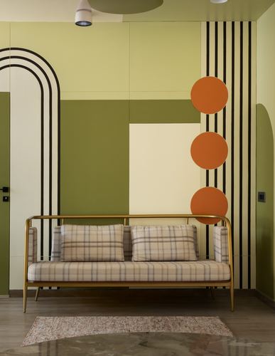 Brass-framed plaid sofa against a bold geometric mural of arches, stripes, and orange circles