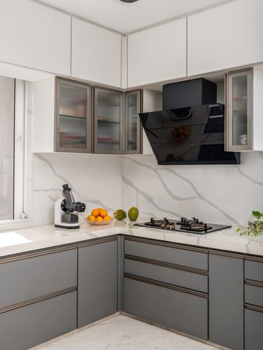 L-shaped modular kitchen with grey cabinetry, marble-look backsplash and black chimney hood