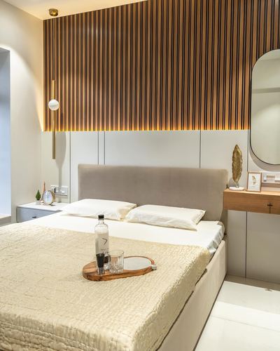 Bedroom with fluted wood accent wall, beige upholstered headboard, and styled bed tray with water bottle