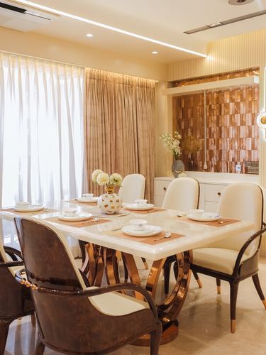 Dining room with marble-top table, cane chairs, and copper textured accent wall