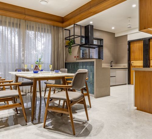 Dining area with marble-top table, wooden chairs, sheer curtains, and open kitchen with teal tile backdrop
