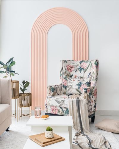 Floral wingback armchair beneath a ribbed pink arched wall panel in a styled living room corner
