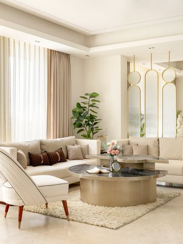 Beige living room with brass coffee tables, cream sofas, and a fluted gold-edged glass screen