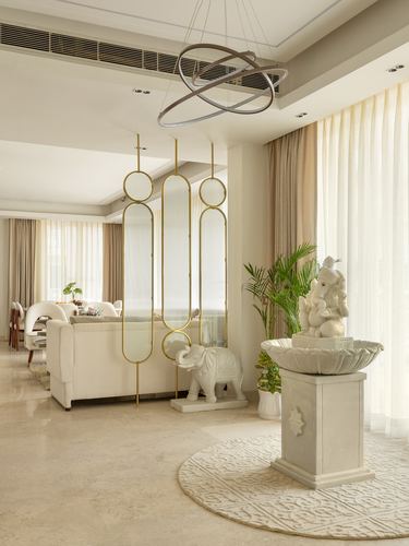 Foyer with marble Ganesha fountain, elephant statue, and gold-framed glass divider leading to living room