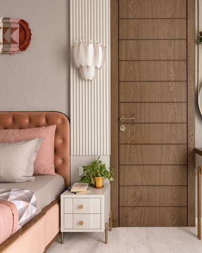 Bedroom corner with tan tufted headboard, fluted wall panel, petal sconce, and walnut panelled door