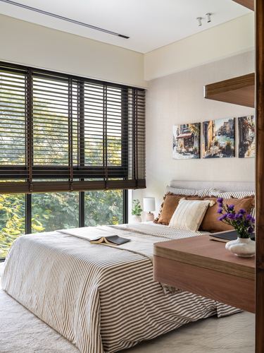 Bedroom with wooden blinds, tree view window, striped bedding, and framed art above headboard