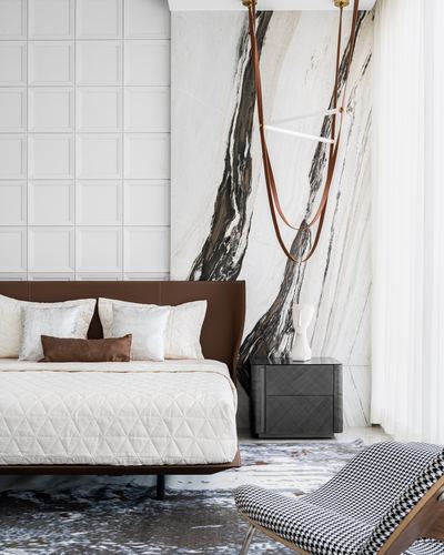 Bedroom with brown leather bed, veined marble wall, and suspended leather-strap pendant light