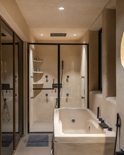 Beige plastered bathroom with glass shower enclosure and built-in tub, black fixtures throughout