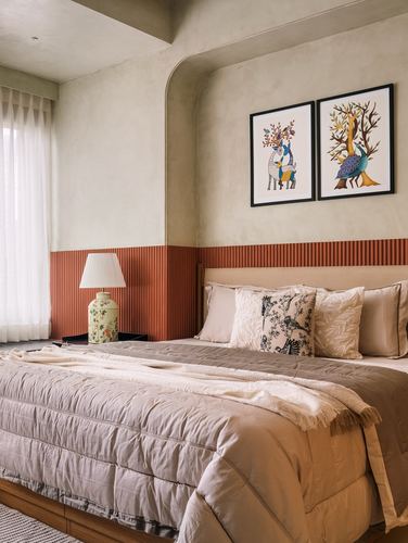 Bedroom with terracotta fluted wainscoting, arched niche, upholstered headboard, and two framed folk-art prints above