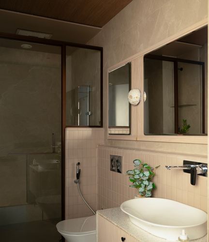 Bathroom with pink tile wainscot, stone walls, framed mirror, vessel sink and glass shower.