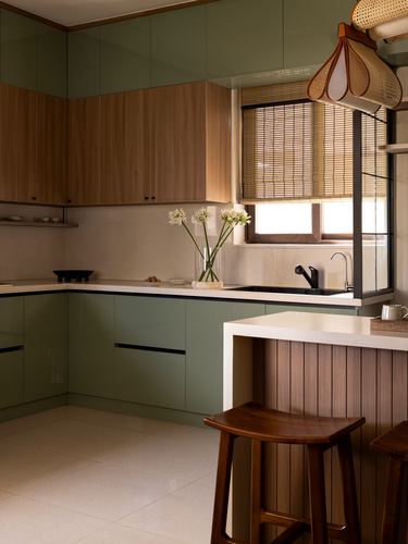 L-shaped kitchen with olive green cabinetry, wood accents, cane pendant lights and a breakfast counter