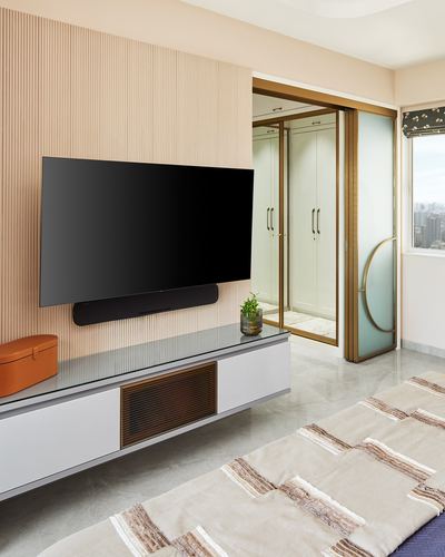 Living room with fluted peach tv wall, floating console, and brass-framed sliding glass doors to wardrobe