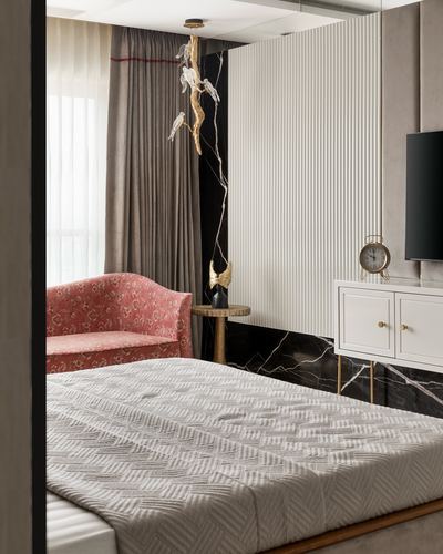 Bedroom corner with fluted panel, black marble accent, pink floral loveseat, and quilted bed in foreground