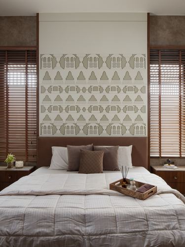 Bedroom with patterned headboard wall, wooden blinds, and neutral bedding with a wooden tray