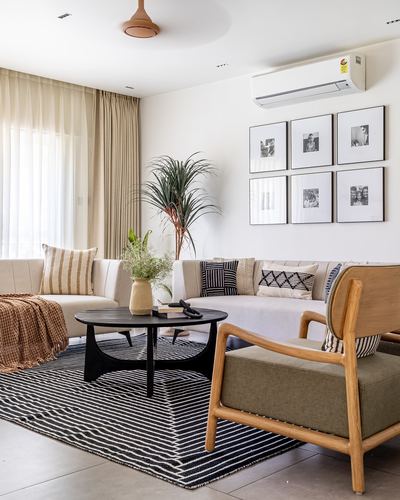 Neutral living room with sectional sofa, black round coffee table, striped rug, and black-and-white gallery wall