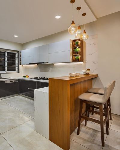 Modern kitchen with wooden breakfast counter, amber pendant lights, and grey overhead cabinetry