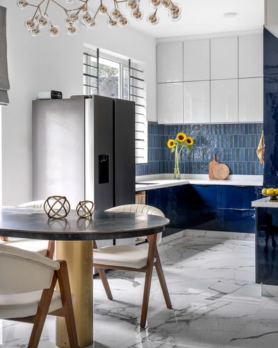 Kitchen with navy glossy cabinets, blue tile backsplash, marble floor and round dining table
