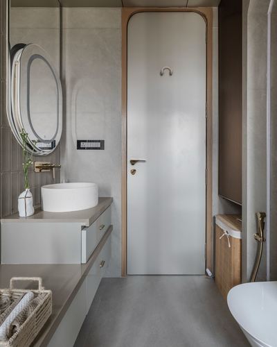 Bathroom vignette with arched door, oval mirror and stone vessel sink in muted grey tones