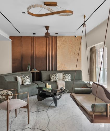 Living room with olive sectional, fluted copper wall, marble floor, and a suspended swing seat