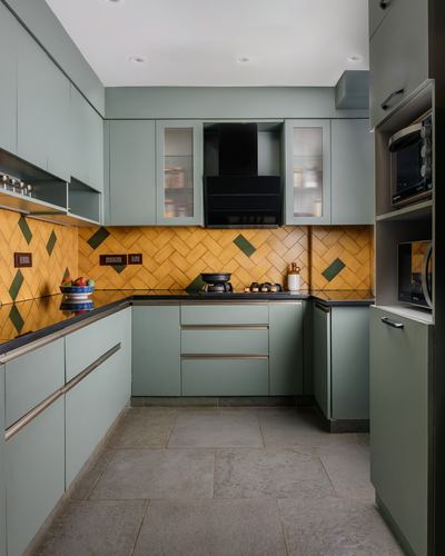 U-shaped kitchen with sage green cabinets and mustard herringbone tile backsplash