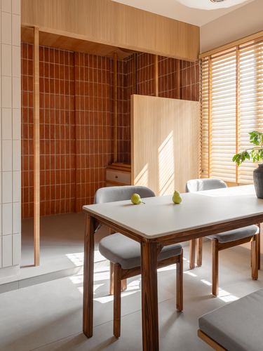 Dining table with grey chairs beside a terracotta-tiled alcove and wooden blinds